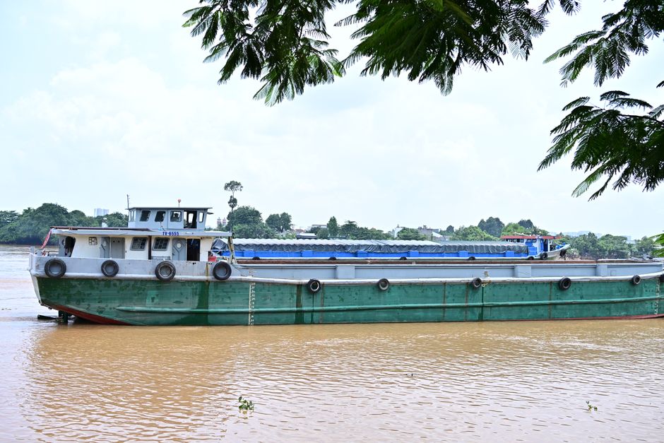 Desenvolvimento Amazonas — A large green cargo boat travels on a muddy river, surrounded by lush greenery and ample